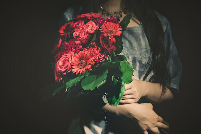 赤いバラの花束を抱える女性